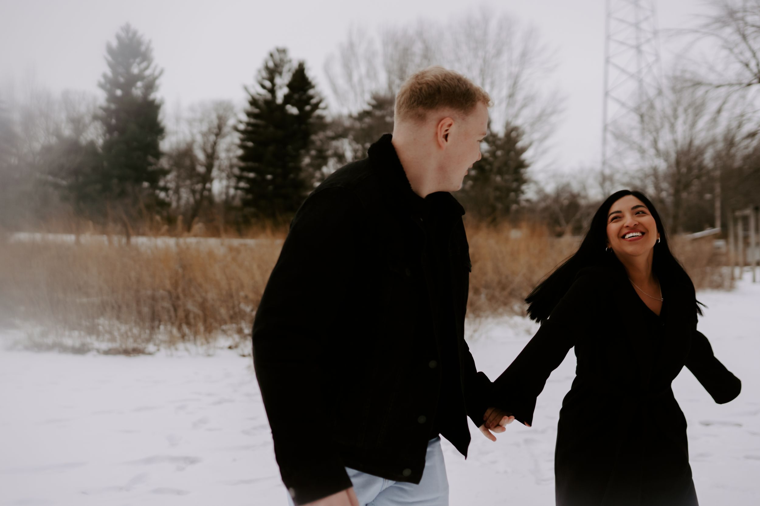 Couple sharing playful and romantic moments during a winter photoshoot in the snow.