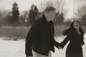 Two people laugh together while walking through fresh snow.