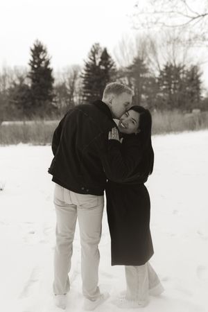 Two people in casual winter wear share a joyful moment in the snow.
