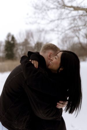 Artistic winter photoshoot capturing intimate moments between a couple in the snow.