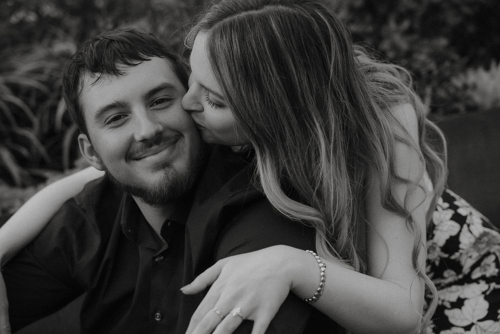 Black and white romantic photo of a couple sharing an intimate moment outdoors together.