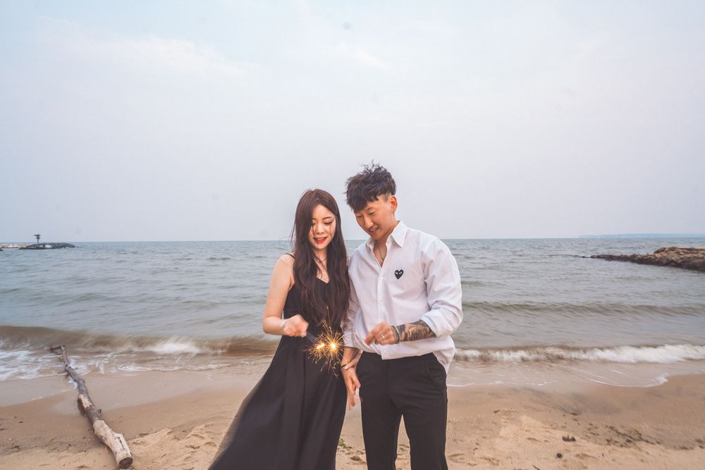 Couple in formal wear walking along beach shoreline.