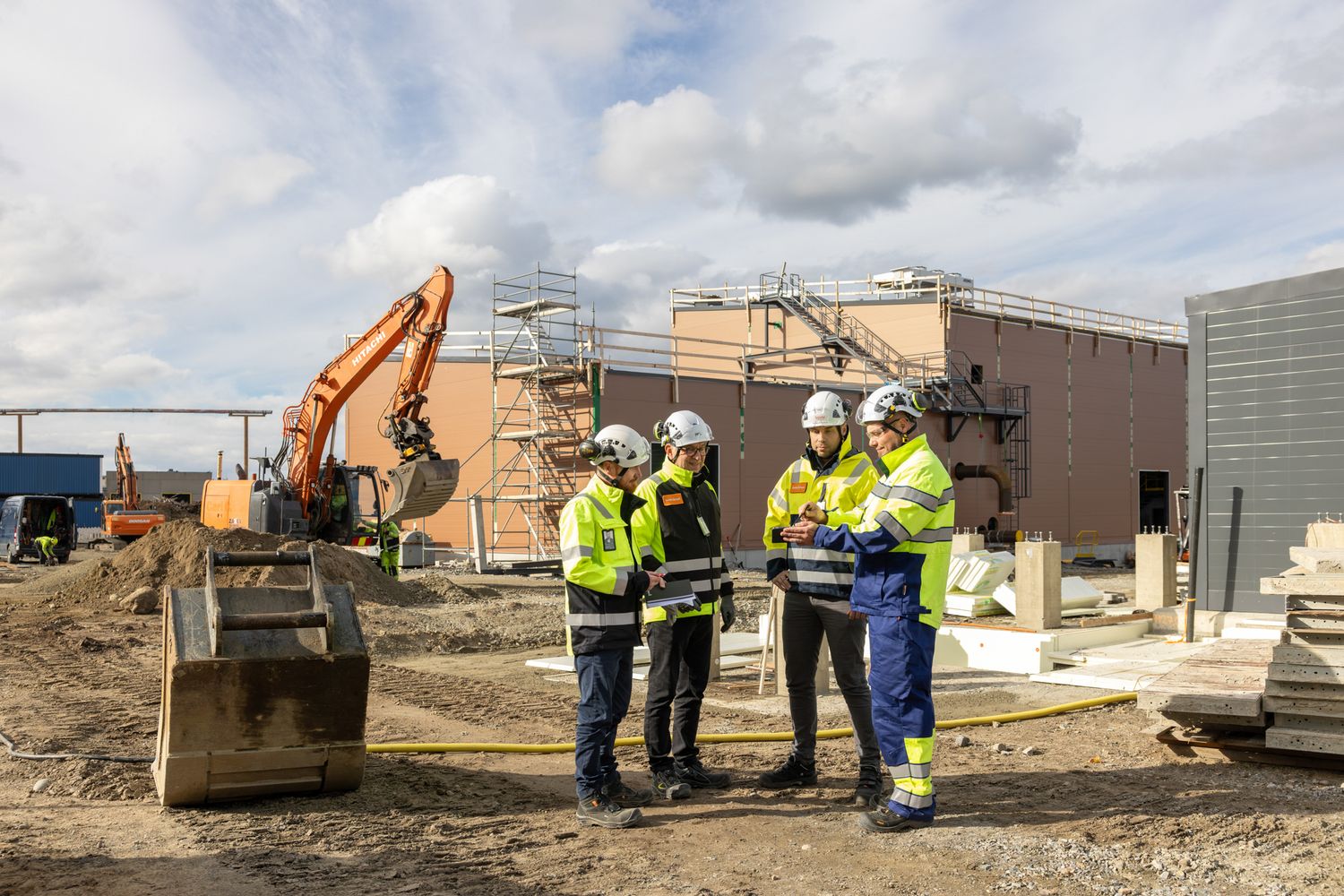 Construction workers and heavy equipment perform earthwork operations at an industrial development site.