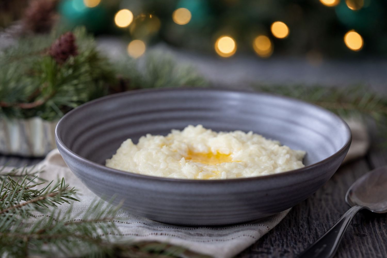 Creamy mashed potatoes topped with melted butter and fresh herbs on dark ceramic plates with holiday decor.