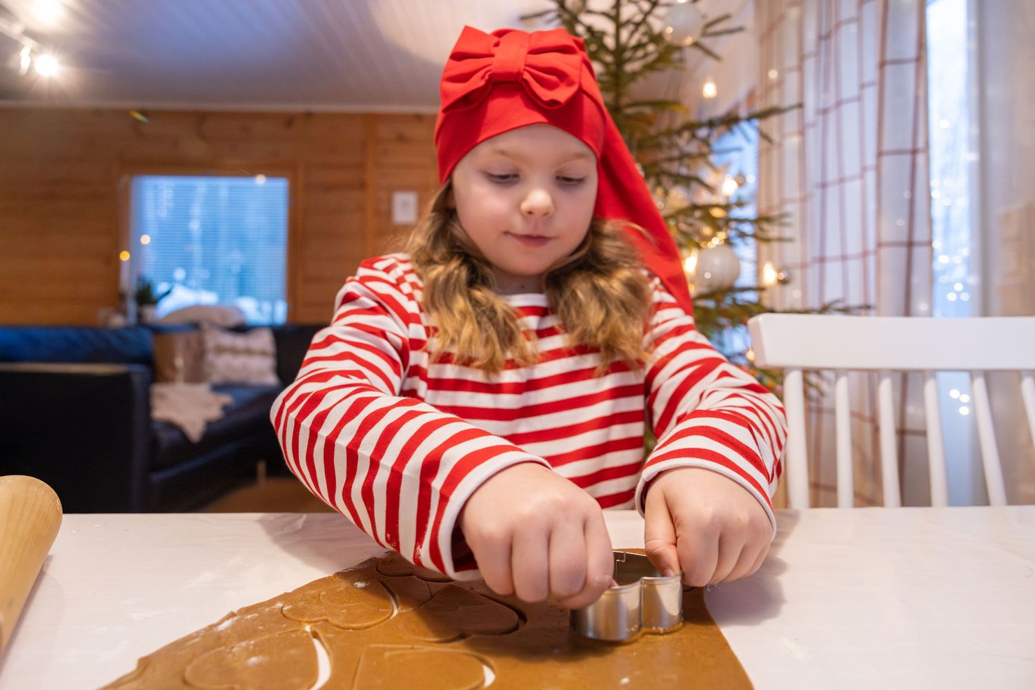 Person wearing red and white striped shirt and red hat sits at table with mobile device.