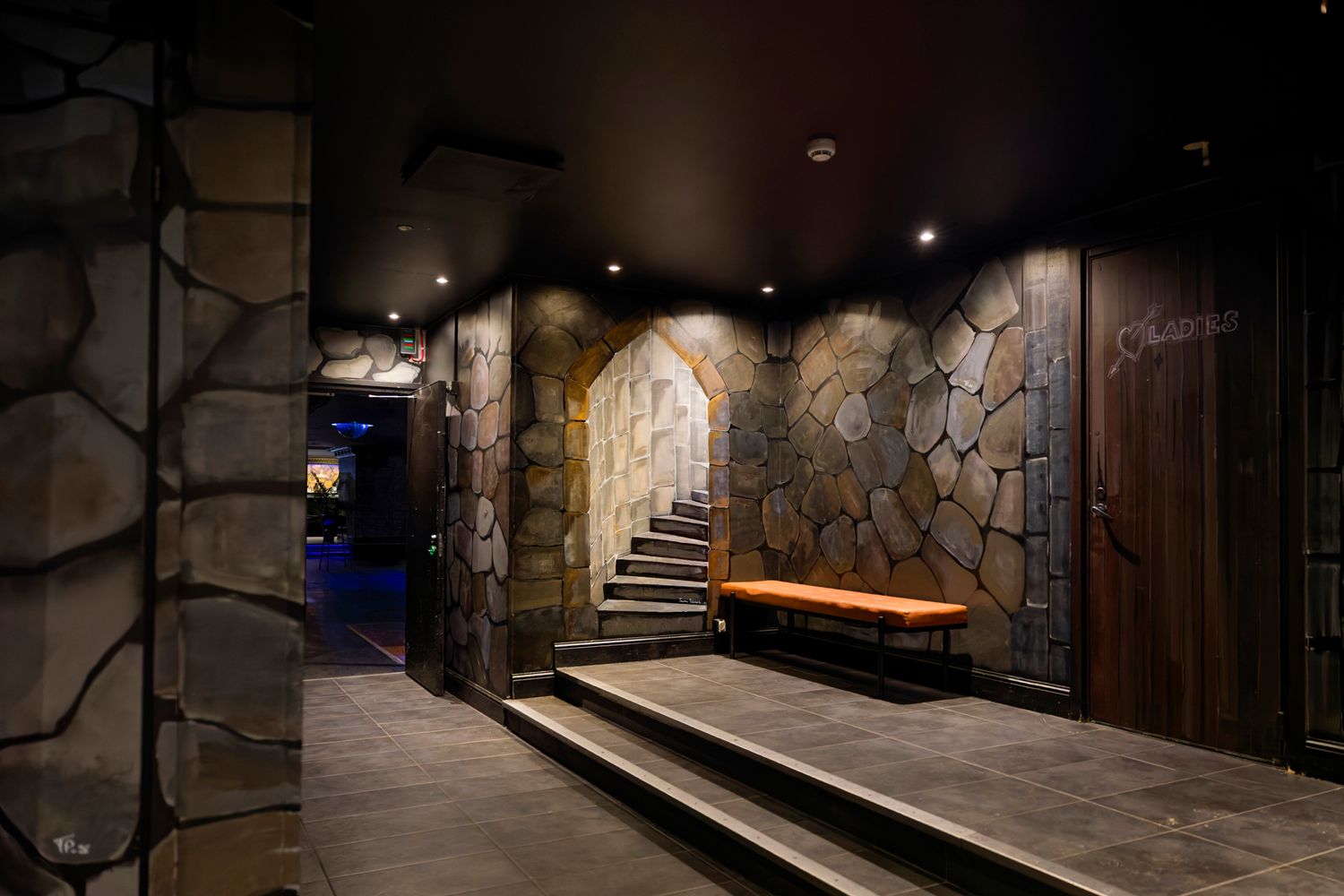 Elegant stone-walled spa corridor with arched doorway, wooden bench, and recessed lighting creating a luxurious ambiance.