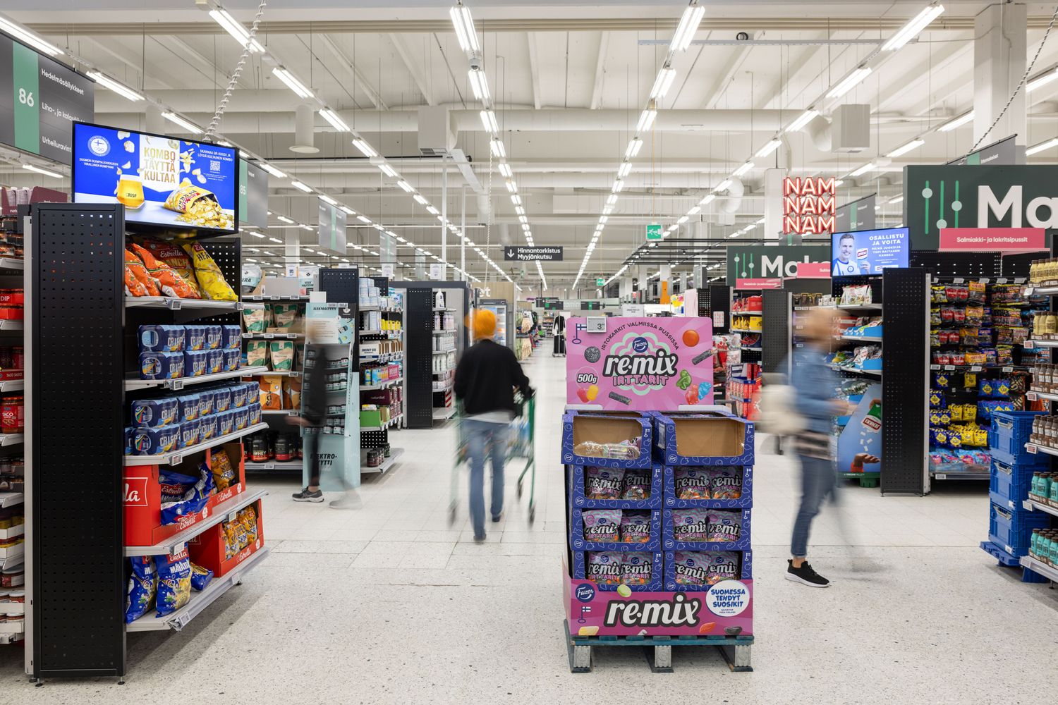 Supermarketin käytäviä, ohikiirehtiviä ihmisiä epäterävänä.