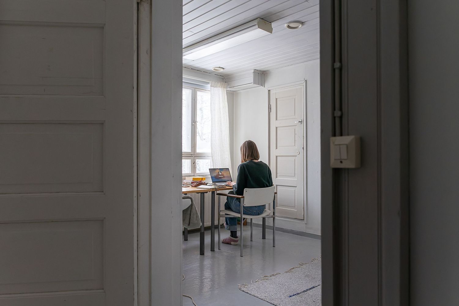 Nainen istuu työpöydän ääressä kirjoittamassa tietokoneella.