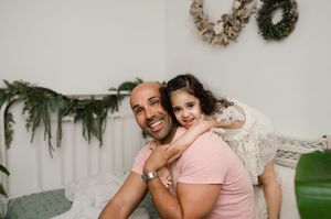 A cozy family cuddles together on a bed decorated with holiday greenery and wreaths.