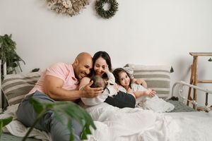 Two people lying in a white bed together while looking at a smartphone in a modern bedroom.