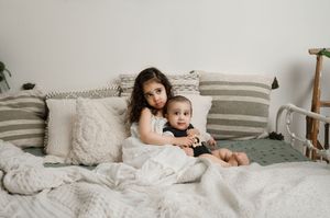 Intimate family moment captured in a sequence of photos showing loving embrace on white bedding.