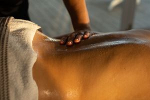 Therapeutic massage treatment being performed on oiled skin in golden sunlight.