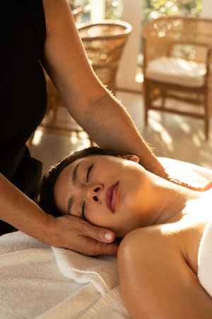 Relaxing spa massage being performed in a sunlit treatment room.