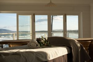 Serene spa room interior with massage tables and natural light streaming through coastal windows.