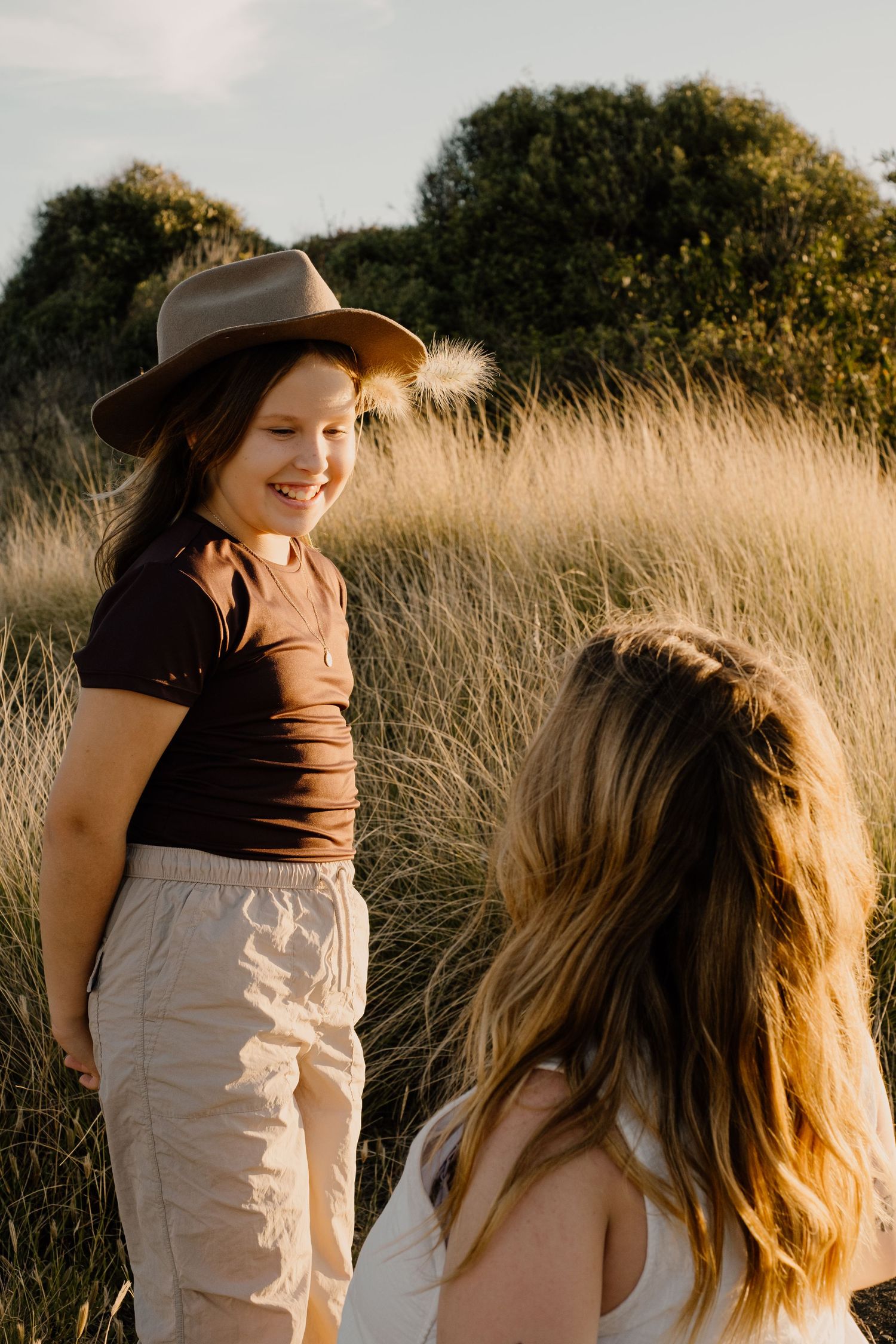 Candid portraits in golden hour light among tall grass meadow.