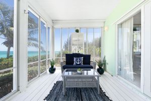 Sunlit sunroom with white walls and window array showing tropical landscaping outside.