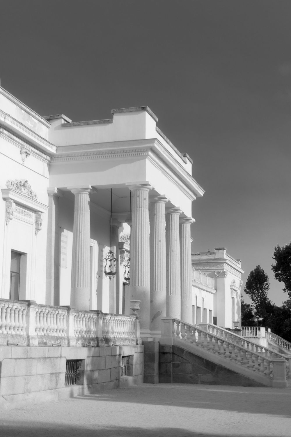Classical white portico with neoclassical columns and stone stairway captured in black and white photography.