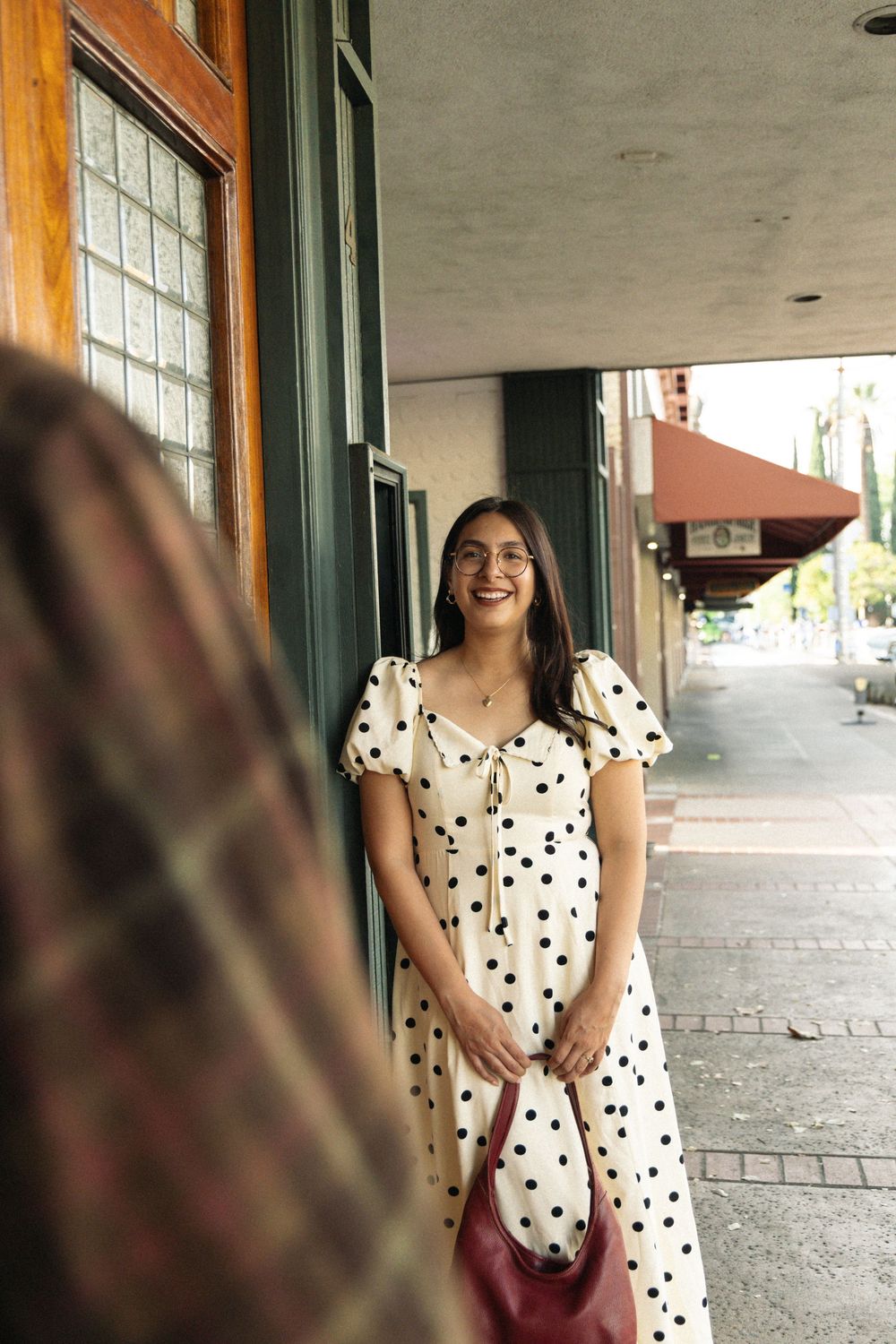 A polka dot dress adorns a casual street scene against wooden storefront windows.