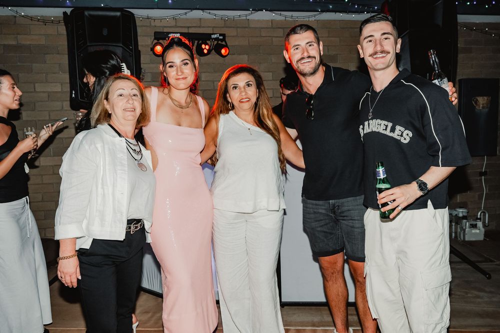 A group of people enjoying drinks at a casual gathering in black and white outfits.