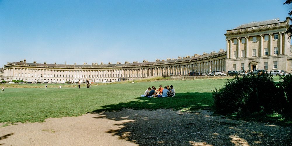 The iconic Royal Crescent in Bath, featuring Georgian architecture and a sweeping lawn under blue skies.