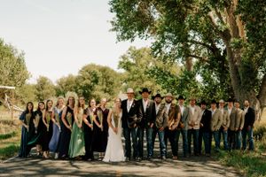A wedding party posing on a country road with trees  around them