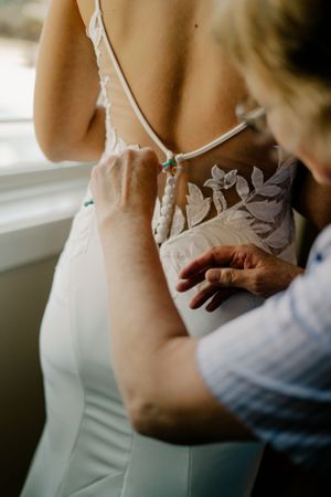 Mother of the bride buttoning her daughters dress