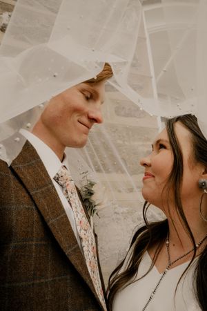 A newly married couple gazing at one another underneath the bride veil