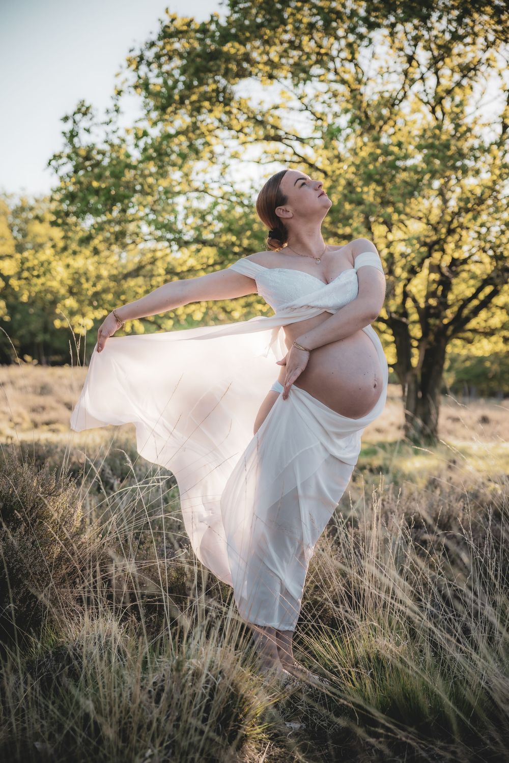 A flowing white dress billows in golden sunlight as a figure dances gracefully among tall grass and autumn trees.