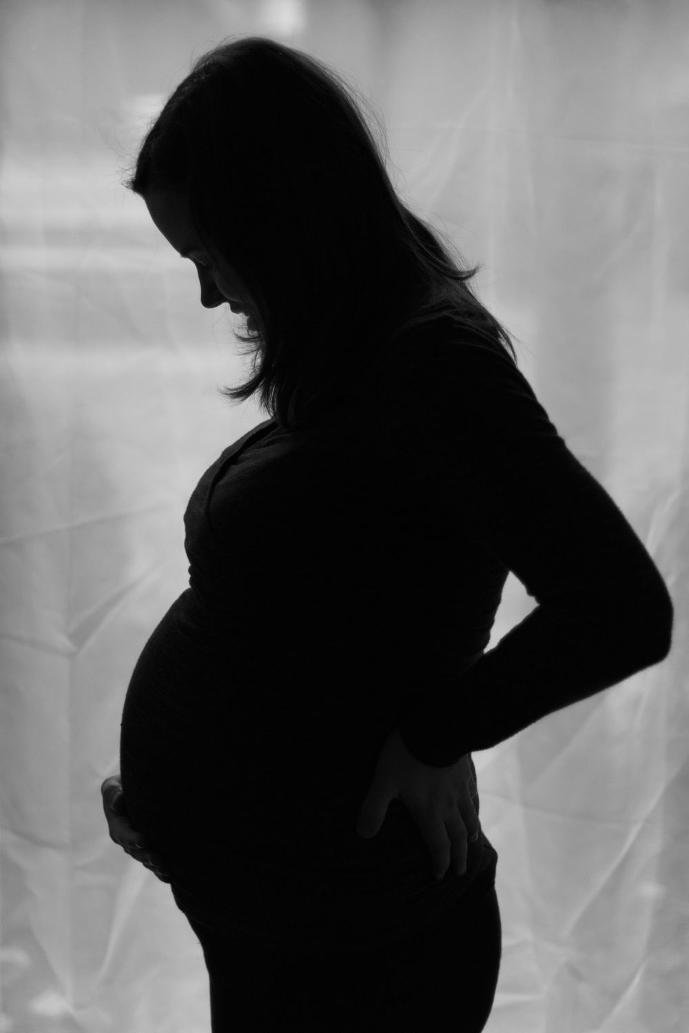 Silhouette of a pregnant woman's profile against a light background.