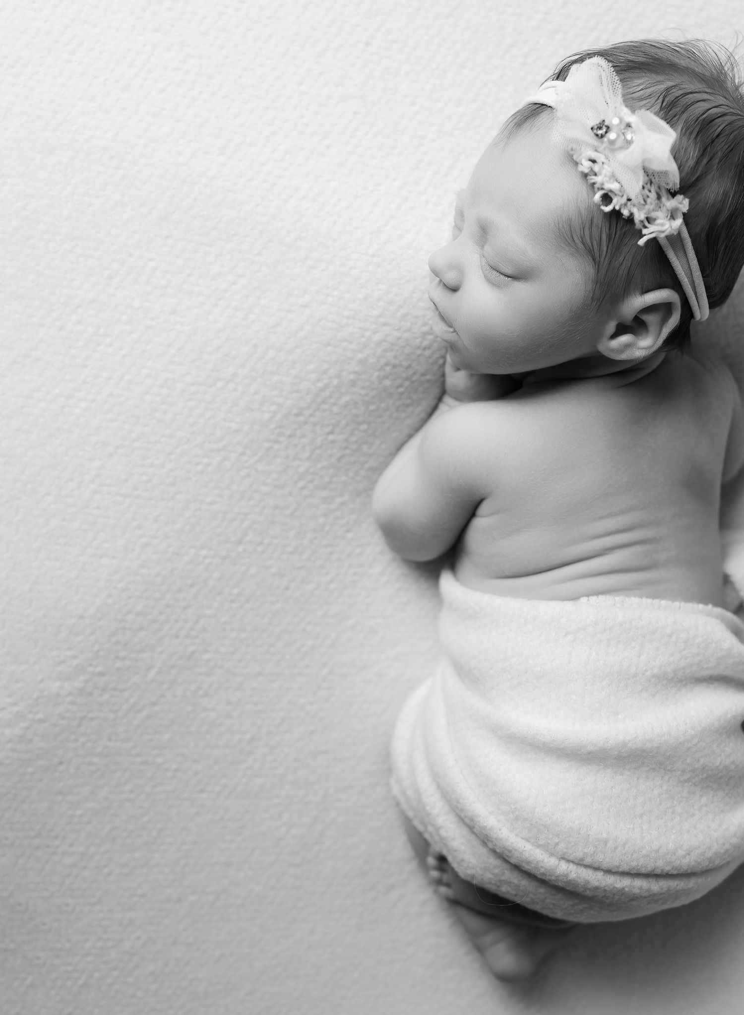 Austin newborn photographer overhead black and white portrait of baby posed on tummy wrapped in soft fabric