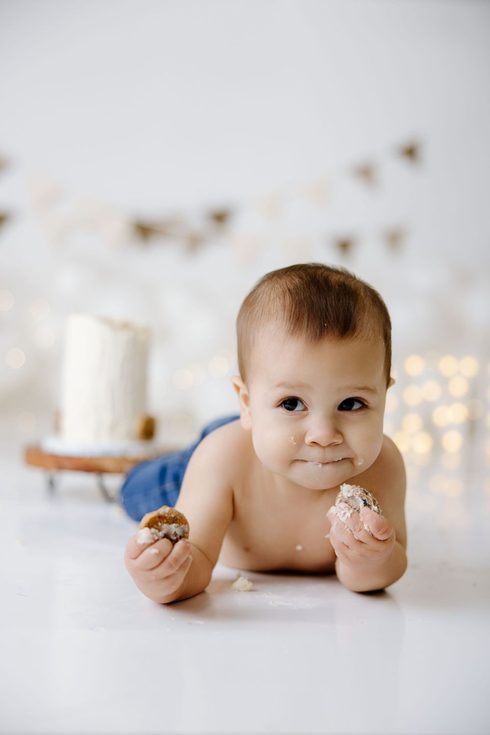 Birthday photo setup with cake and twinkle lights on white background.