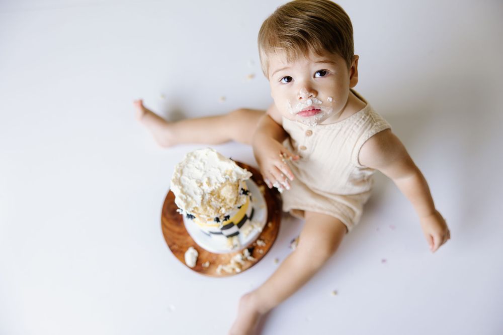 Overhead view of birthday cake smash photo session on white background.
