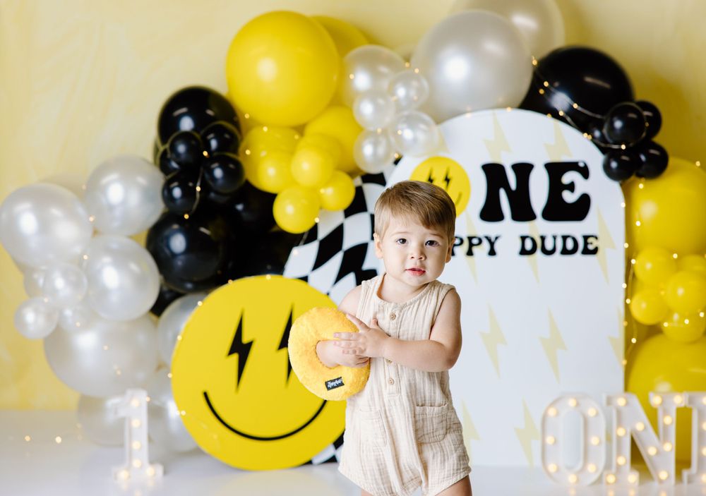 Birthday party decorations with yellow smiley face balloons and black and white accents.