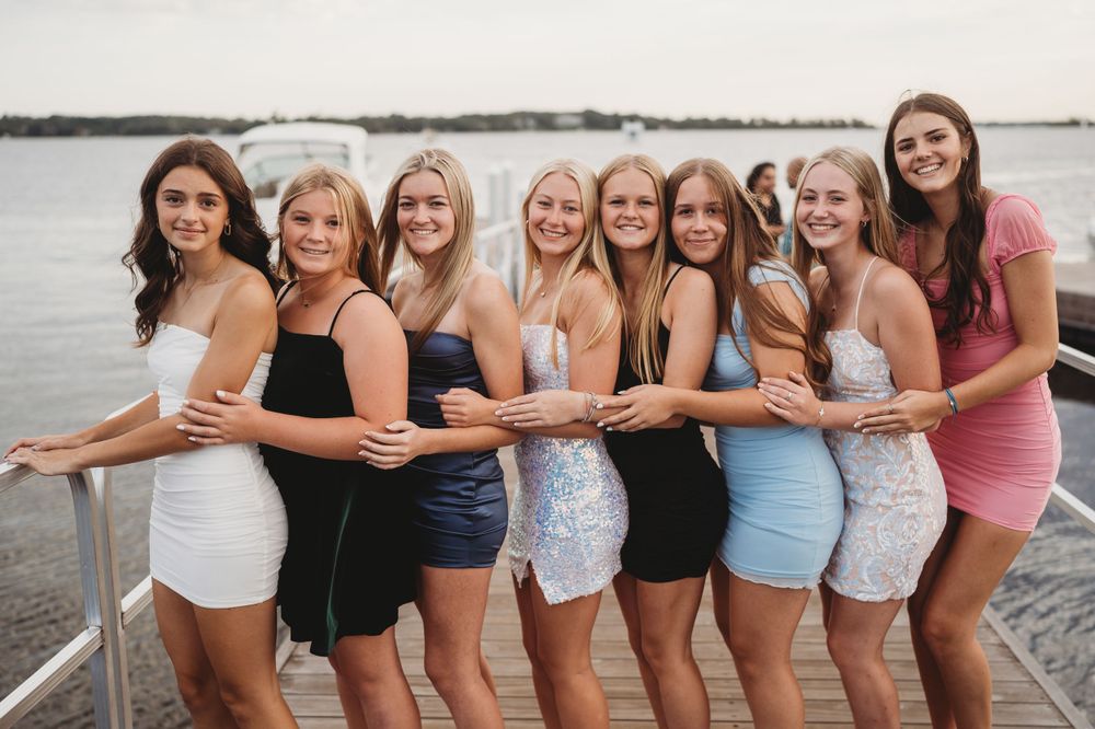 Friends lined up along a railing wearing summer outfits and laughing together.