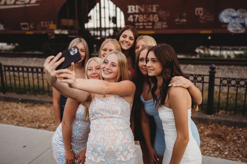 Group photo session near a BNSF train car with friends in summer attire.