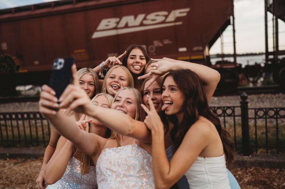 Friends sharing genuine laughter during a photoshoot by railway tracks.