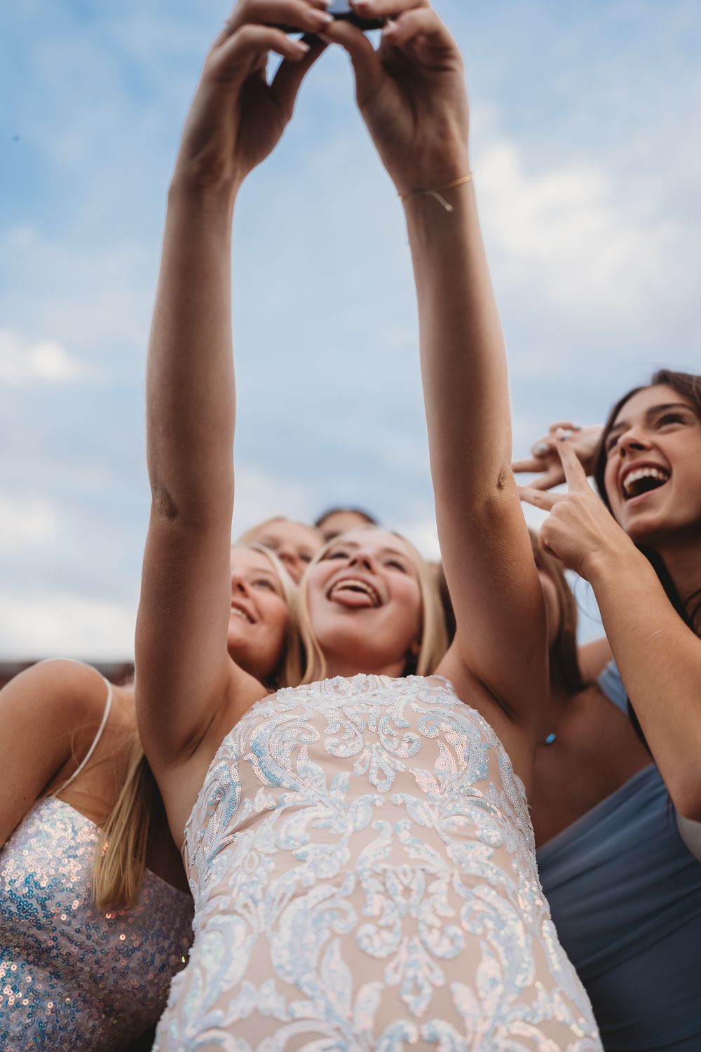 Upward angle shot of friends laughing together against a blue sky background.