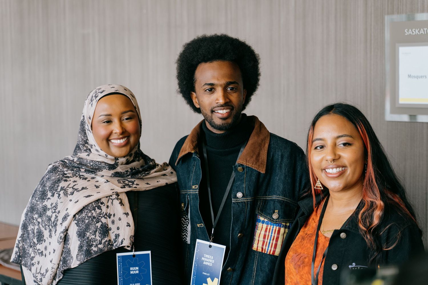 Three smiling people posing together at a Samsung event wearing name badges.