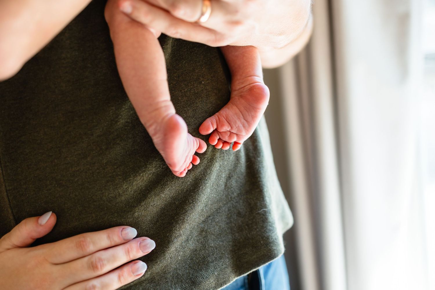 Close-up of a newborn baby's tiny feet cradled gently in a parent's hands.