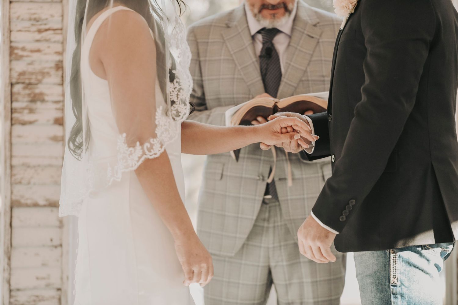 a groom holding a brides hand during their wedding ceremony