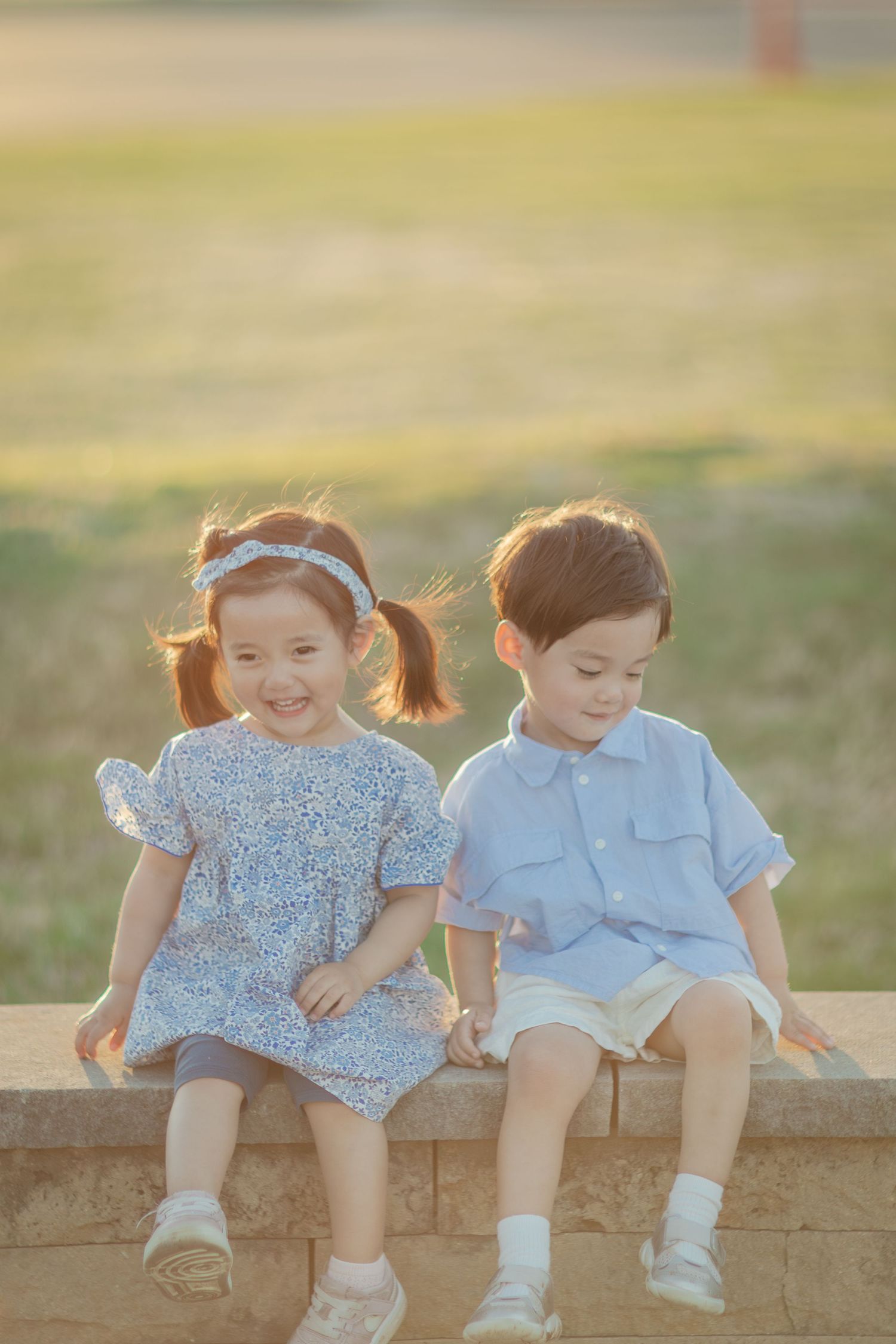 Three-year-old toddlers sitting together in warm golden hour backlight at Cedar Lake during a Saint Louis Park family photography session.