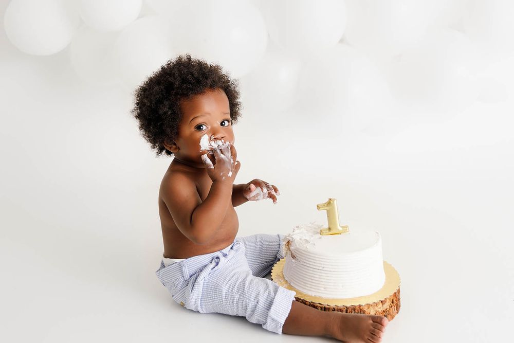 A baby boy celebrates his birthday smashing a white cake by Moreno Valley baby photographer.