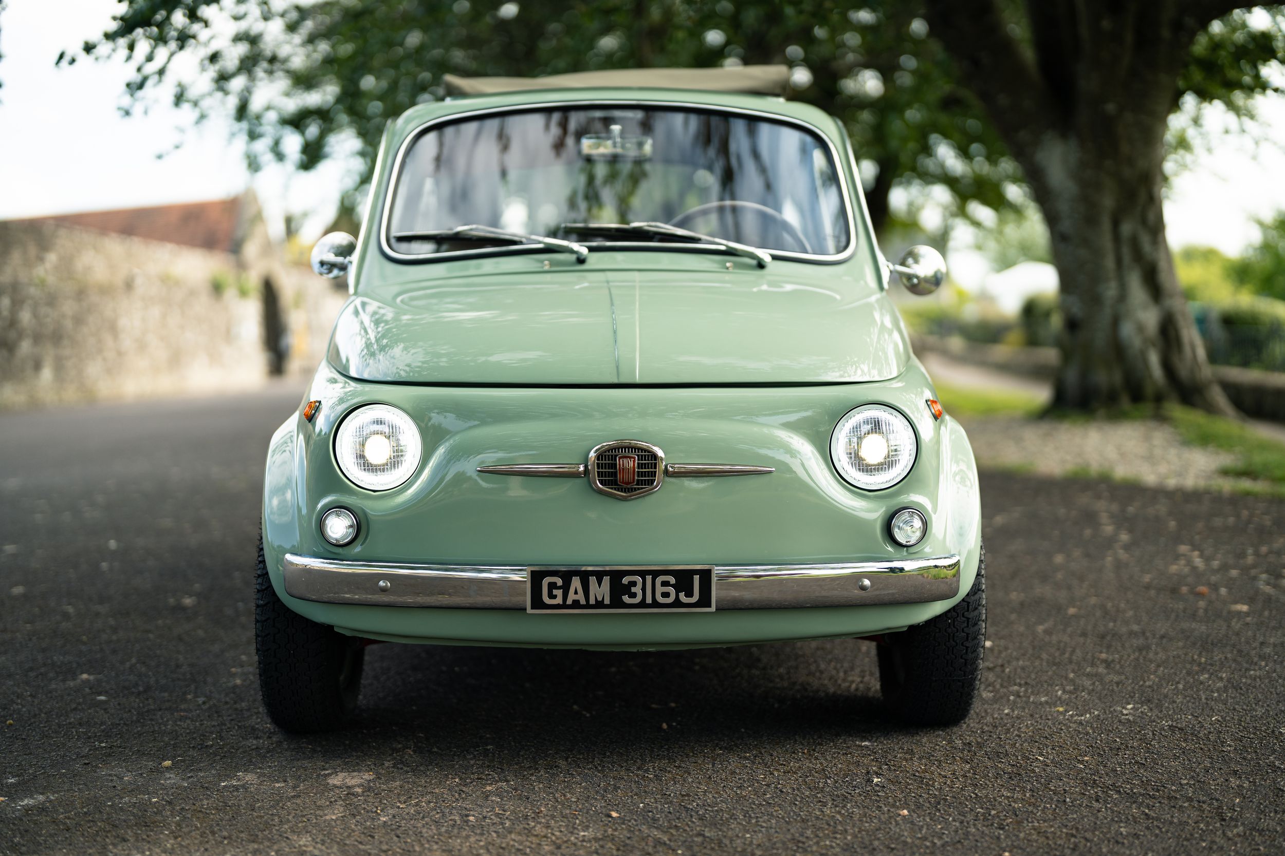 Mint green vintage Fiat 500 classic car front view on a quiet road, UK registration plate GAM 316J.