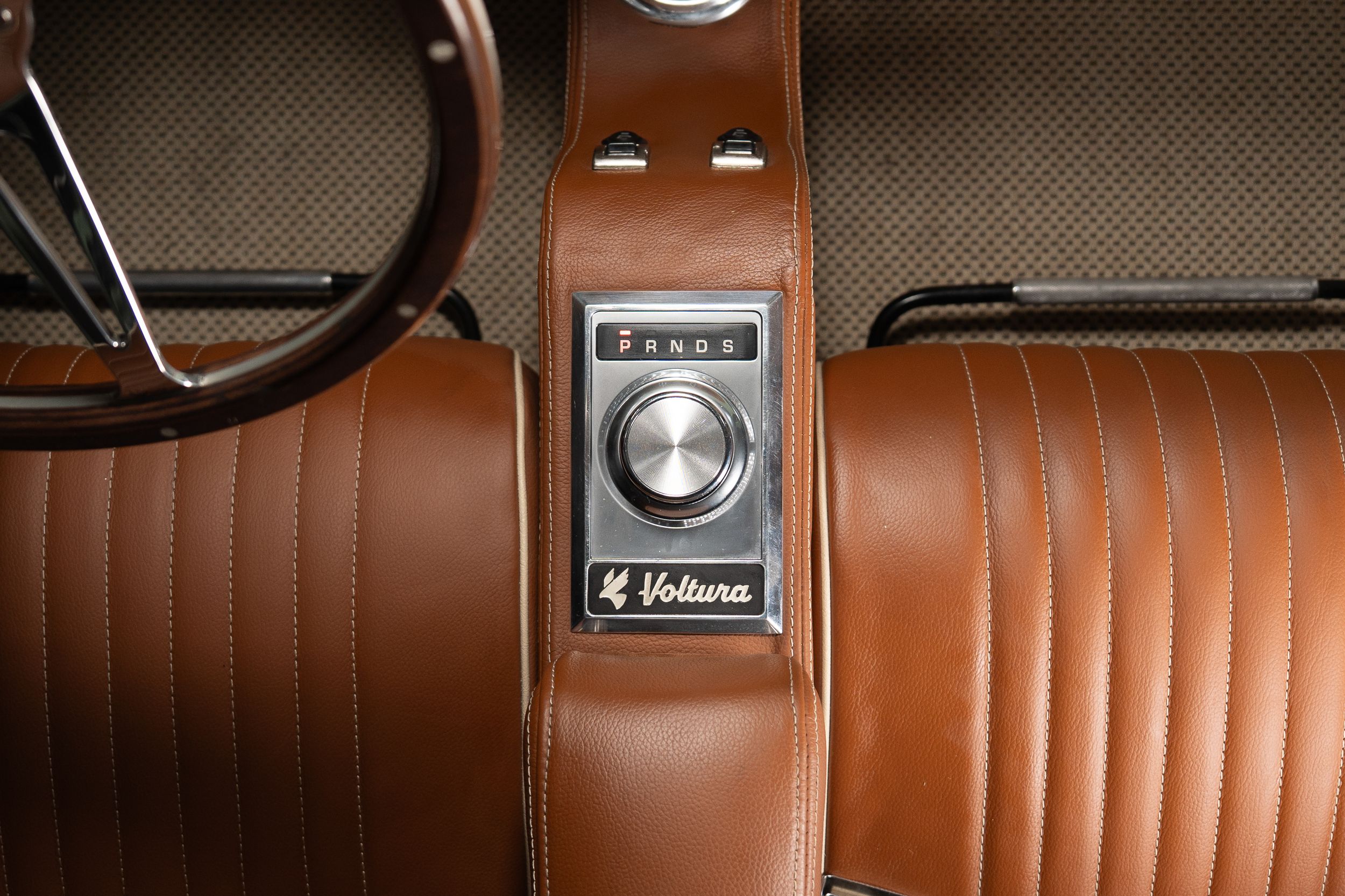Close-up of a La Voltura classic car interior featuring rich tan leather seats and a vintage Fandor control panel.