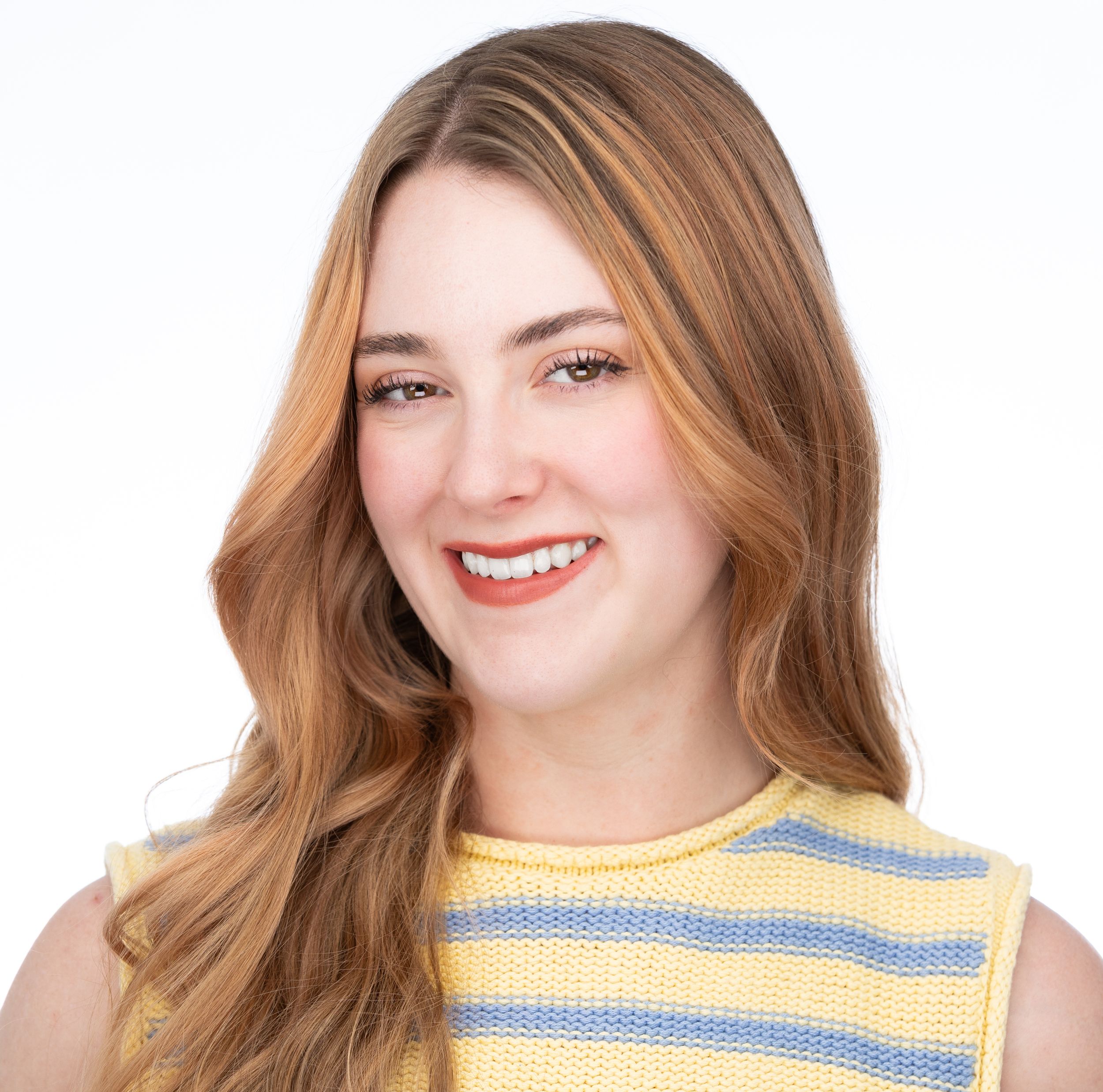 Professional headshot of smiling young woman with auburn hair wearing yellow striped top.