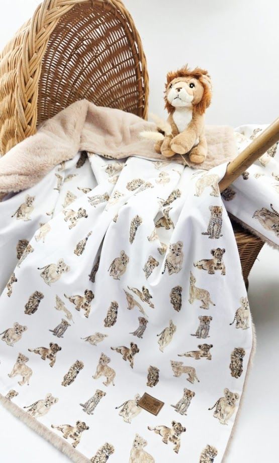 Cozy nursery corner with a white BABY sign, giraffe stuffed animal, and patterned blanket on a wicker chair.