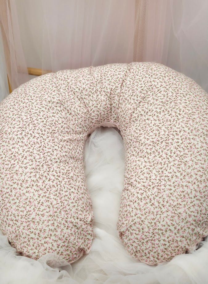 Floral print nursing pillow with pink rose pattern on white fabric, C-shaped pregnancy support cushion.