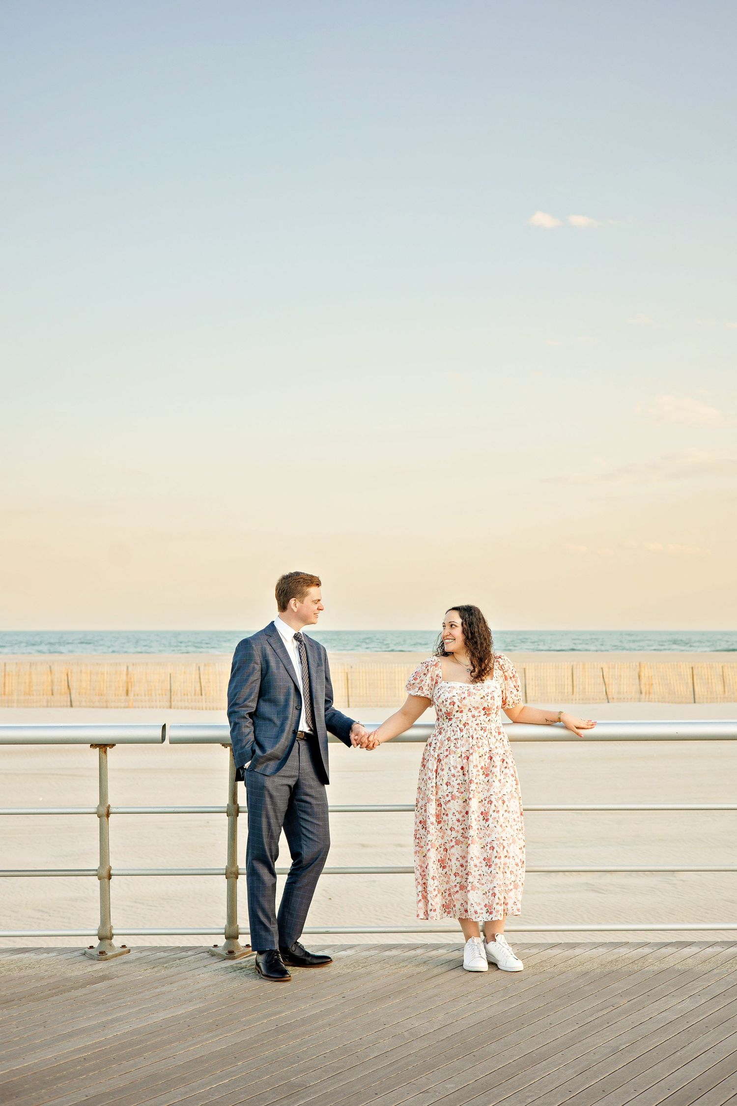 A romantic proposal scene set between rows of grapevines in a scenic vineyard with white flowers and a blanket.