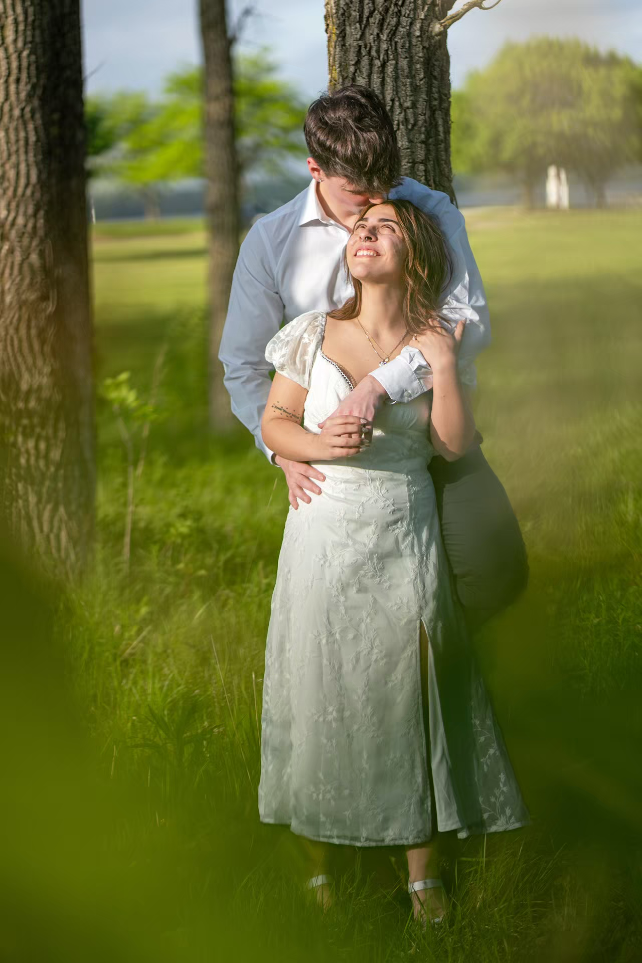 Romantic couple embracing near a tree in a lush green park, at Alum Creek Beach