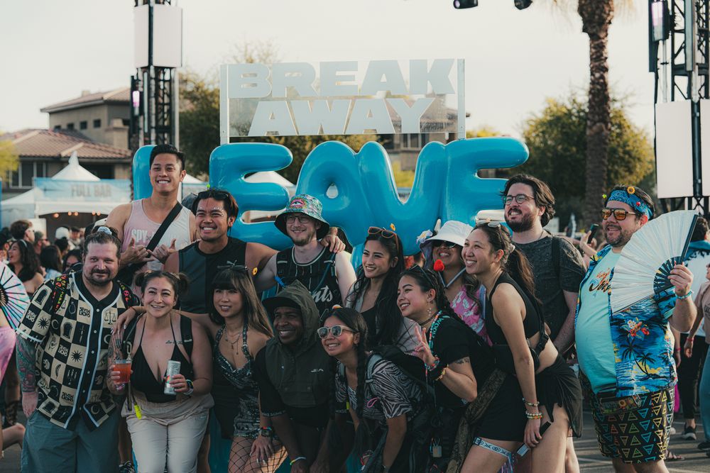 Group of friends posing together at Breakaway music festival with colorful balloon letters outdoors.